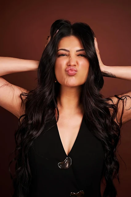 Shruthi Hassan posing stylishly in a black sleeveless top.