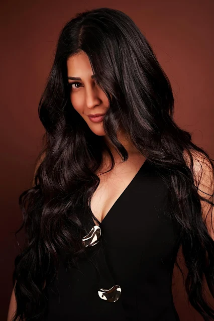Shruthi Hassan posing stylishly in a black sleeveless top.