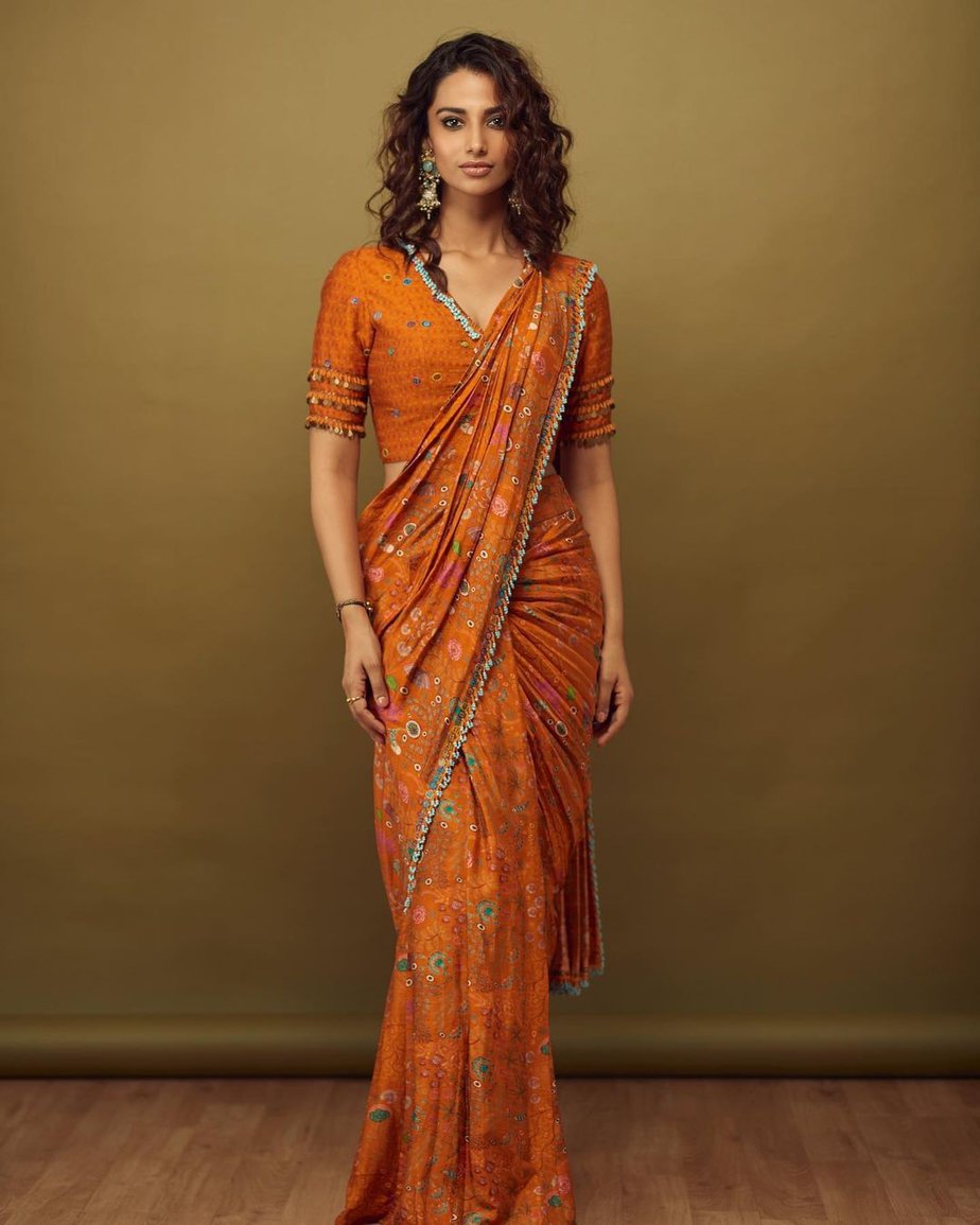 Meenakshi Chaudhary’s glam look in an orange pre draped saree! Sarees